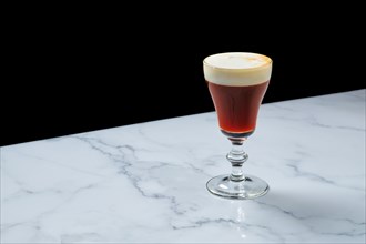 Glass of espresso martini cocktail on marble table with copy space for text
