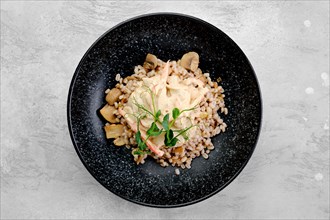Boilet pearl barley with fried mushrooms and creamy flour sauce on a plate