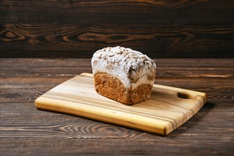 Loaf of artisan rye bread with flour topping on wooden cutting board