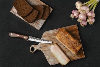 Overhead view of smoked fat with brown bread on wooden cutting board