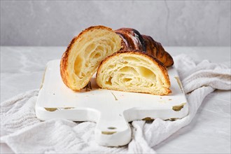 Cross section of classic croissant on marble background and white wooden board