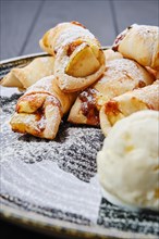 Close up view of baked pear wrapped in pastry with cinnamon served with ice cream