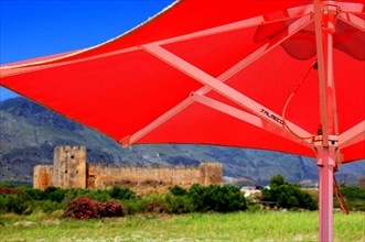 Red parasol and the fortress of Frangokastello on the south coast of the Mediterranean island
