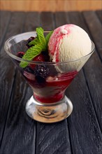 A cup of raspberries ice cream decorated with dewberry and mint leaves