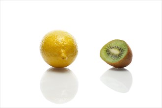 Lemon and kiwi with reflection on white glass table