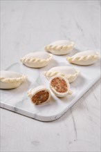 Frozen dumplings stuffed with beef meat and provencal herbs on marble serving plate
