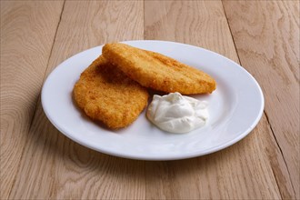 Potato cutlet in breading stuffed with ham served with sour cream on wooden table