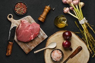 Overhead view of raw beef petite sirloin with ingredients on black background
