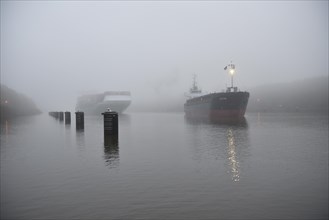Container ship is overtaken by cargo ship in Kiel Canal in fog