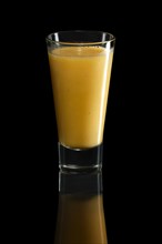 Glass of orange and mango cocktail isolated on black