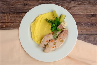 Top view of cold boiled pork with potato puree and pickled cucumber