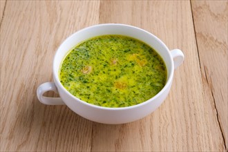 Green soup with asparagus and small sausage on wooden table