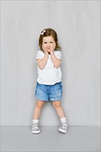 Two years old girl in white t-short and jeans shorts posing in studio