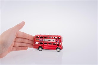 Child hand playing with London double decker bus model on white background