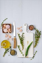 Overhead view of wooden cutting board with fresh thyme and spices for piquant sauce or marinade on wooden kitchen table