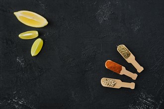 Top view of small wooden spoons with spice on black background