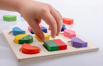 Colorful wooden pieces of a logic puzzle in hand