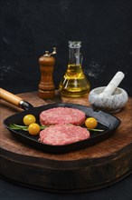 Raw beef burger patty on cast iron pan