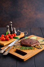 Juicy grilled beef steak and zucchini served with fresh tomato cherry and basil on wooden cutting board
