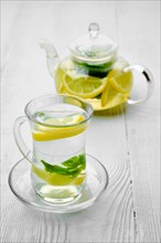 Antioxidant hot drink with lemon and mint in transparent tea pot and glass