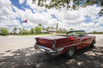 Classic convertible car with monument cuban flag background