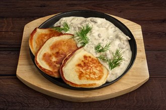 Flapjack with mushroom sauce on wooden plate. Top view