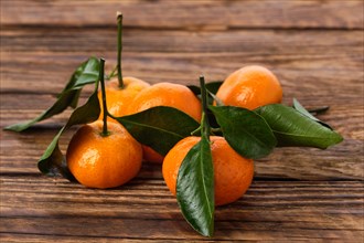 Fresh small mandarines with leaves on wooden background
