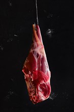 Fresh raw lamb leg bone in on butcher hook