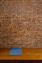 Gym mat on wooden podium with brick wall on background