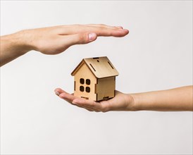 Hands protecting wooden cottage