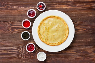 Top view of thin pancakes with assortment of jam and sauce