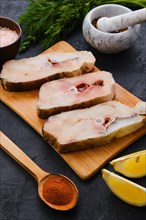 Top view of fresh raw cod steak on wooden cutting board with spice
