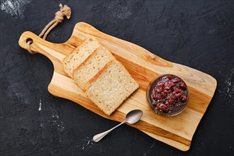 Top view of transparent pot with cherry jam and toast bread