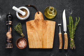 Overhead view of empty wooden cutting board with spice for steak and knife and fork with horn handle