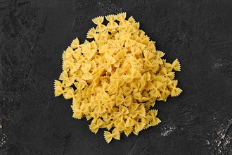Top view of raw farfalle pasta with spice and herbs on black background