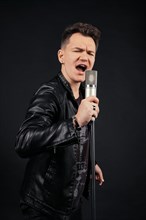 Low key portrait of man singing and holding microphone