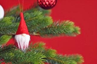 Decorated Christmas tree with cute Christmas gnome tree ornament on red background