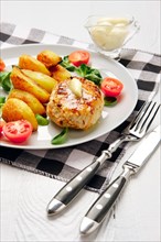 Fried chicken cutlet with potato slices served with tomato cherry and corn salad. Traditional belorussian food