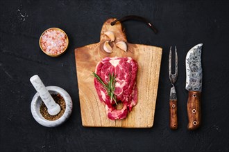 Fresh raw lamb neck on wooden cutting board with herbs and seasoning