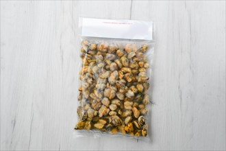 Cooked frozen peeled mussels meat in vacuum packaging on wooden table