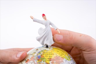Hand holding a Sufi Dervis on a globe