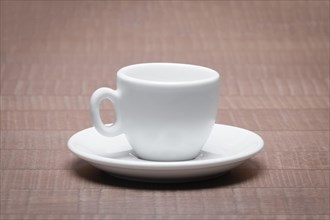 Clean and empty ceramic cup for espresso with saucer on wooden table