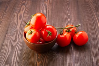 Branch of fresh tomatoes on wooden table