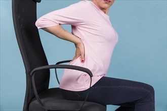 Woman sitting chair having backache blue backdrop. Resolution and high quality beautiful photo