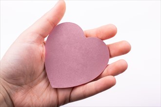 Pink color heart shaped paper in hand as love concept