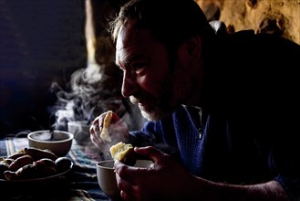 Man eating steaming hot potatoes for traditional breakfast of the Indios