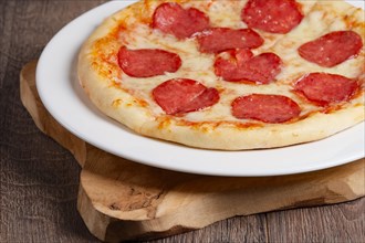 Part of pizza pepperoni on wooden plate