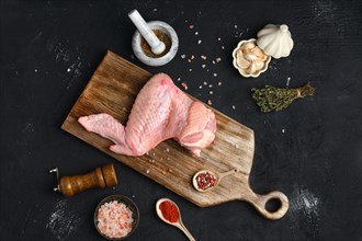 Raw turkey wing on wooden cutting board