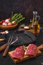 Fresh lamb or veal prime steak on cutting board with herbs