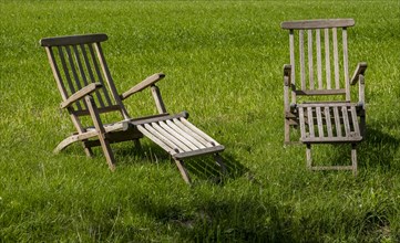 Two teak deck chairs in a meadow